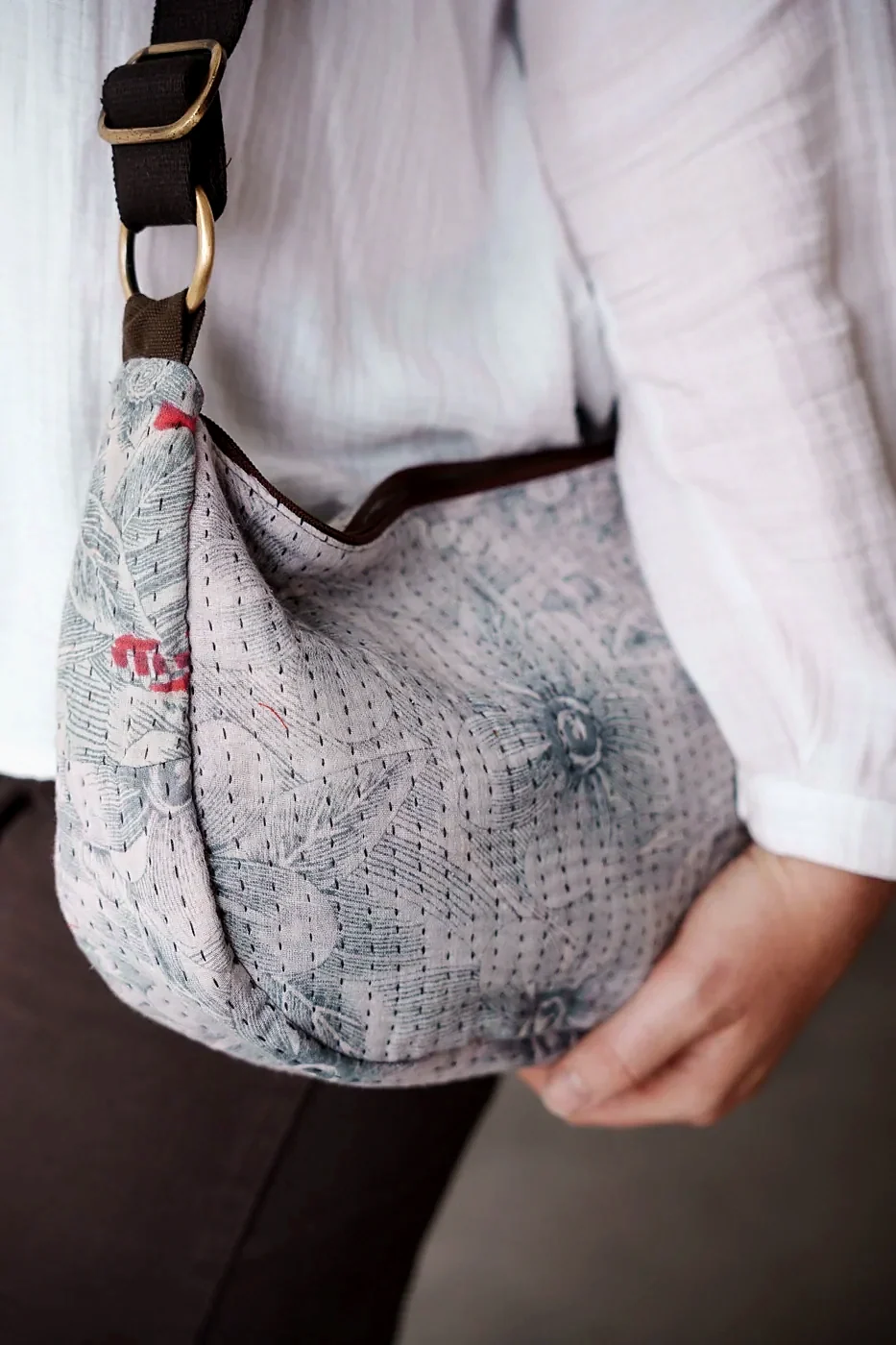 A hand-stitched kantha shoulder bag in soft grey and blue sari fabric.